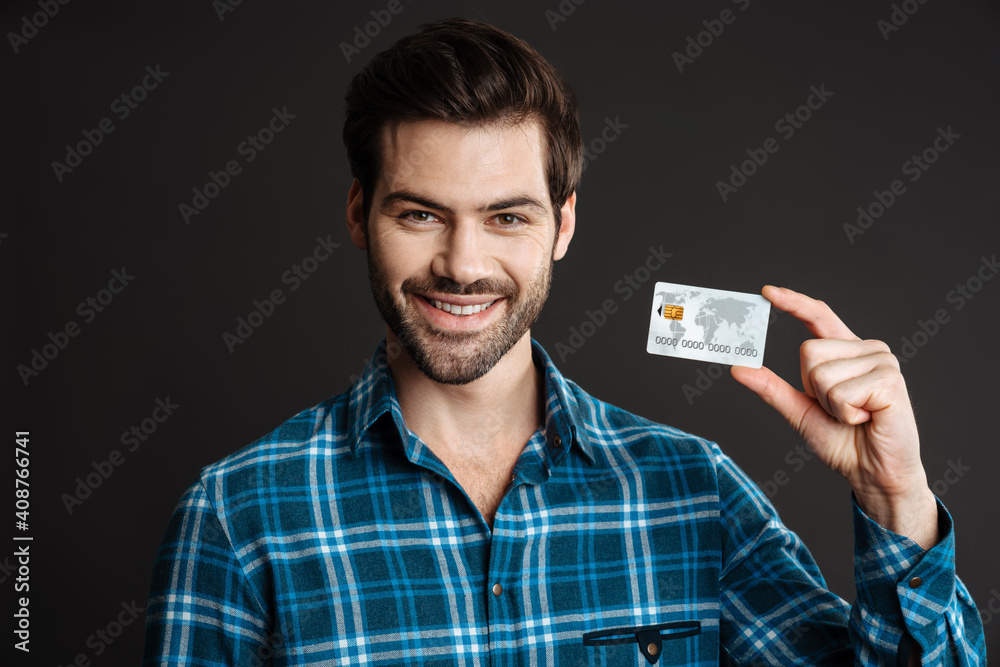 Happy unshaven guy smiling while posing with credit card Happy unshaven guy smiling while posing with credit card