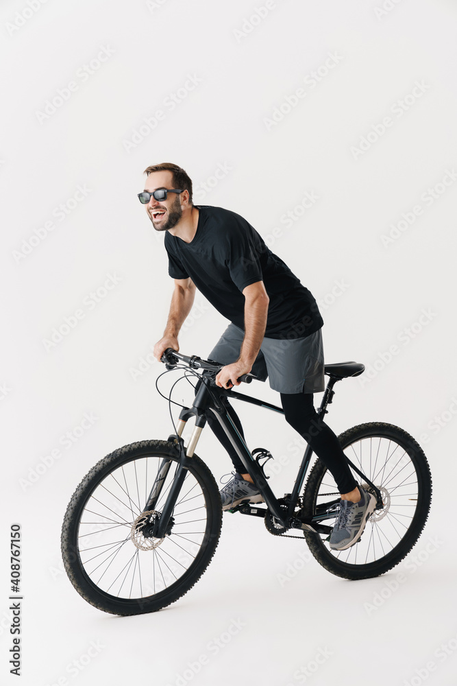 Excited young sportsman in sunglasses riding his bicycle