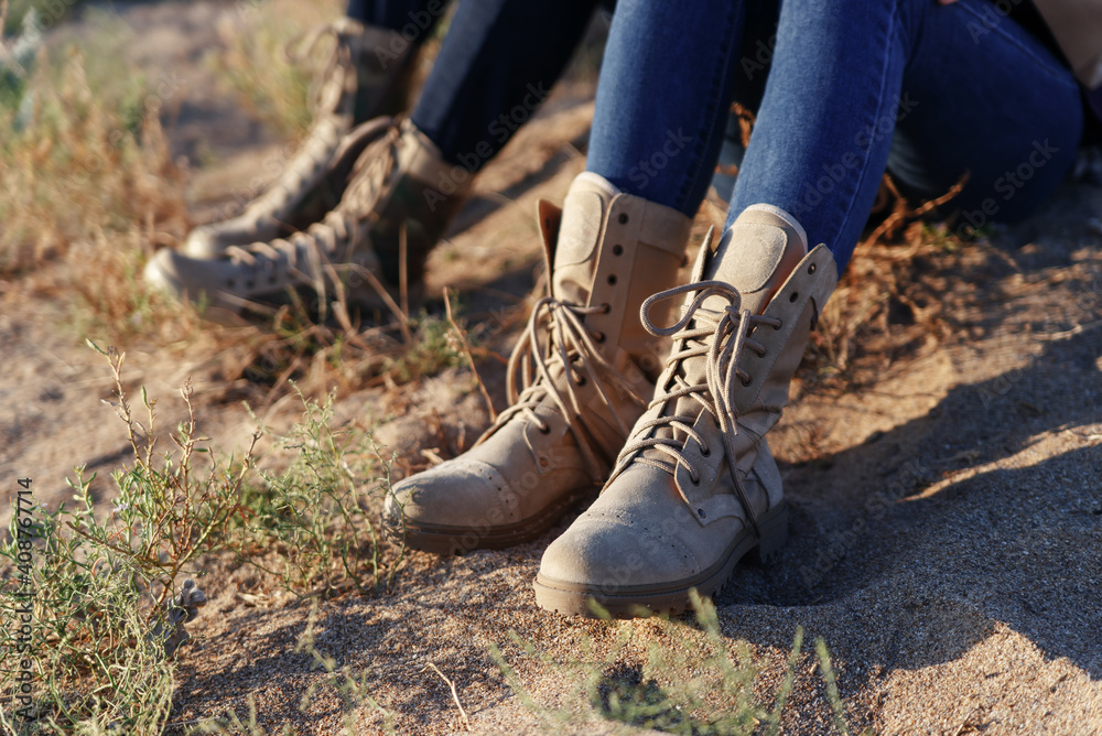 Male and female legs in army beige boots and jeans. Outdoor activities couples in the wilderness Male and female legs in army beige boots and jeans. Outdoor activities couples in the wilderness