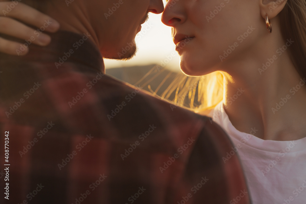 Close-up cropped portrait of a beautiful young couple waiting to kiss against sunset light.