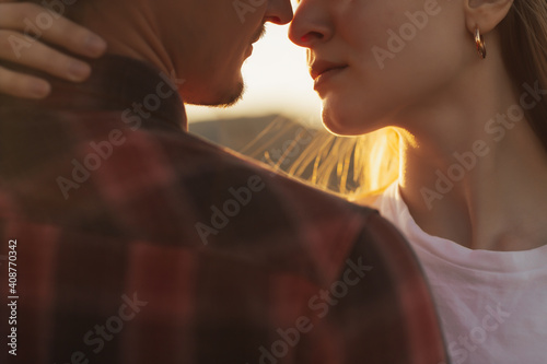 Obraz na płótnie Close-up cropped portrait of a beautiful young couple waiting to kiss against sunset light. w salonie