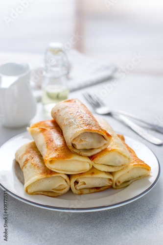 Served breakfast table with stuffed pancakes on a white plate, selective focus
