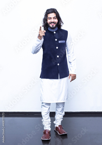 Pakistani Man Pointing with both hands fingers at right side with corse legs on white background at studio. photo