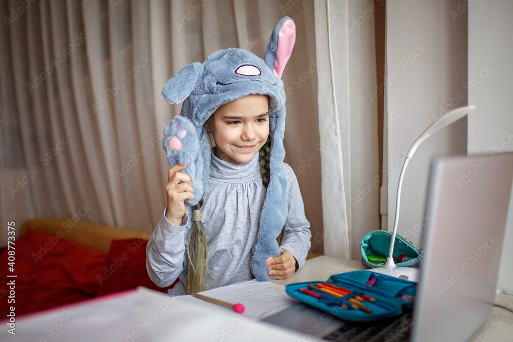 Distant education, online class meeting. Girl wearing funny hat for amusement during online lesson Distant education, online class meeting. Girl wearing funny hat for amusement during online lesson