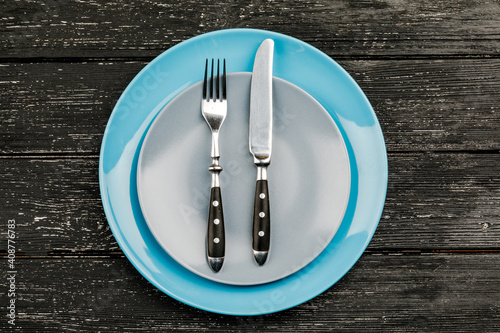 Empty plate with cutlery on a wooden table.