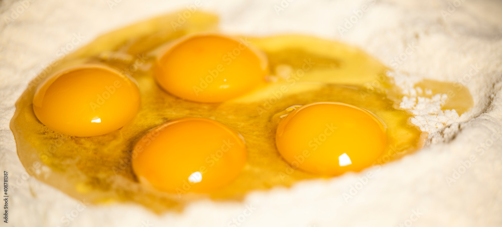 (Selective focus) Close-up view of a heap of flour with some fresh eggs inside. Flat lay, Ingredients for a homemade dough such as pasta, bakery, cakes etc. (Selective focus) Close-up view of a heap of flour with some fresh eggs inside. Flat lay, Ingredients for a homemade dough such as pasta, bakery, cakes etc.