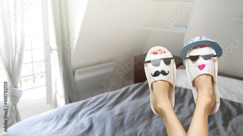 Canvas Print Funny female legs wearing slippers with funny faces lying in bedroom and dreamin