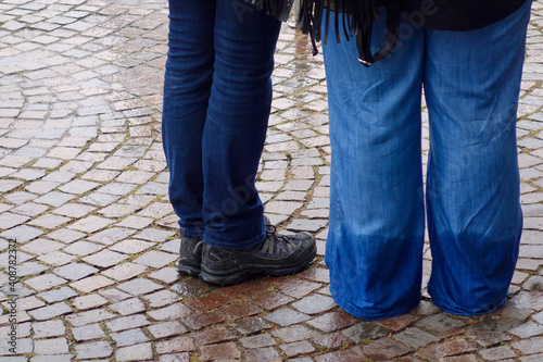 Φωτογραφία Legs of 2 people standing, 1 wearing wet jeans
