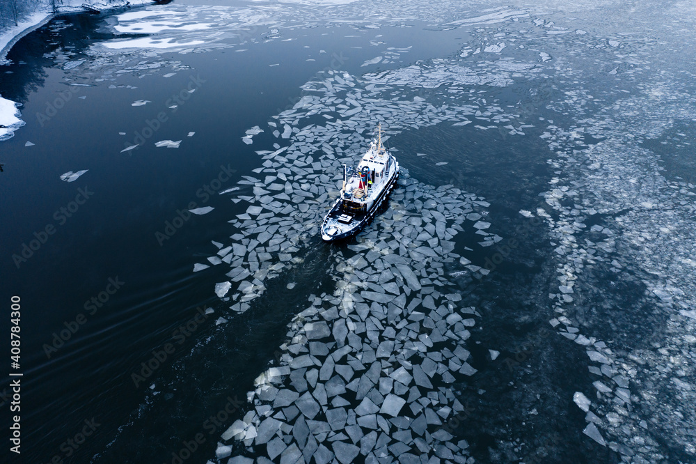 Tug boat pushing through the ice on a sea in winter