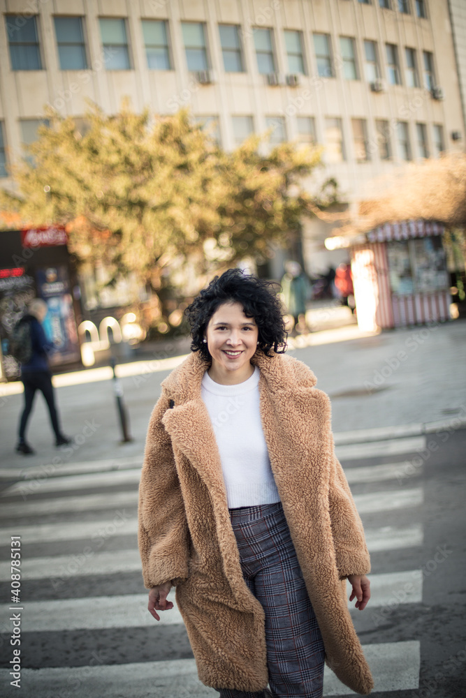 Fototapeta premium Happy smiling woman walking on street, and looking at camera.