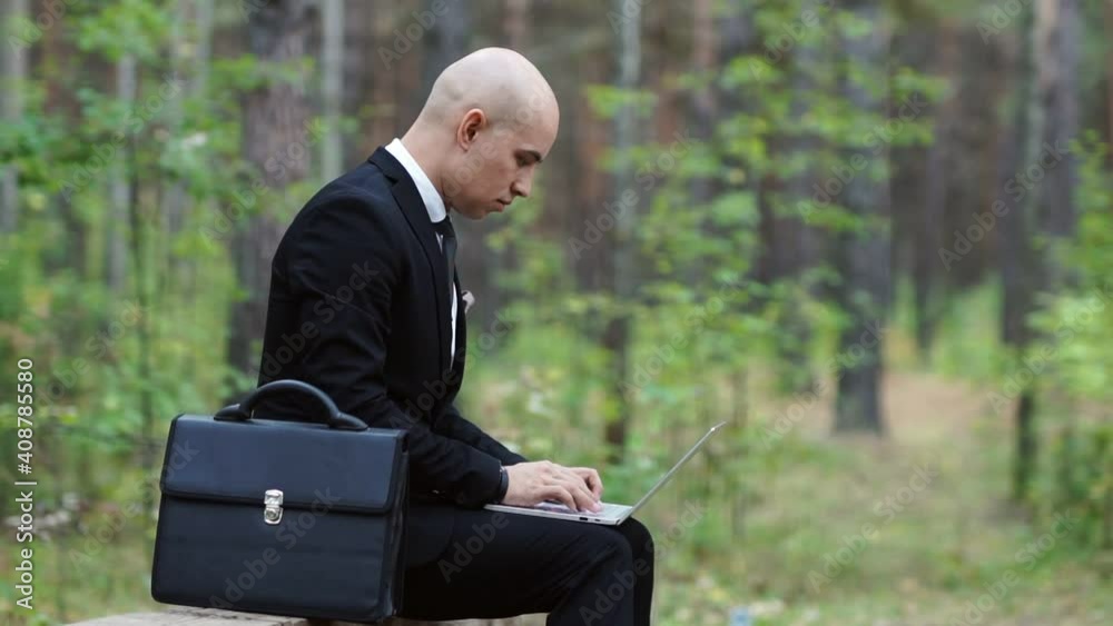 A man in a business suit works at a laptop