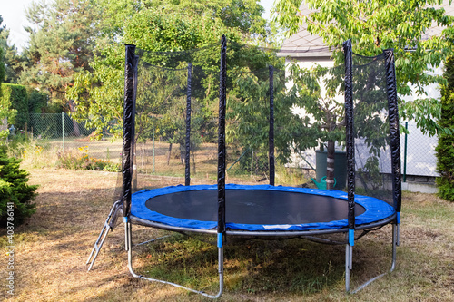 Obraz na płótnie Trampoline with safety net on the lawn in a backyard. Front view of trampoline in a garden. Trampoline jumping. w salonie