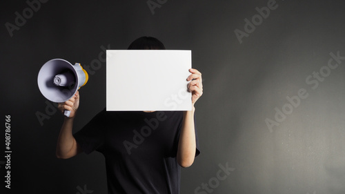 Empty space for text.female or woman hands is holding blank A4 white paper and megaphone on black background.she wear black t shirt
