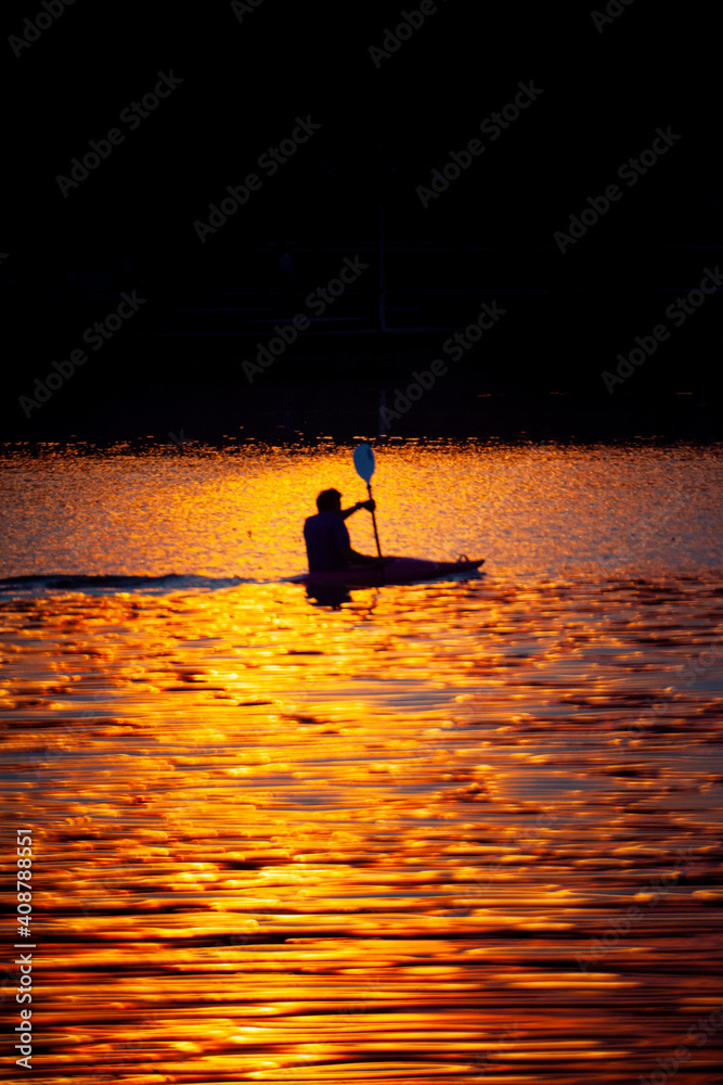 Rowing athletes train for victory in the evening during the low sun before the horizon.