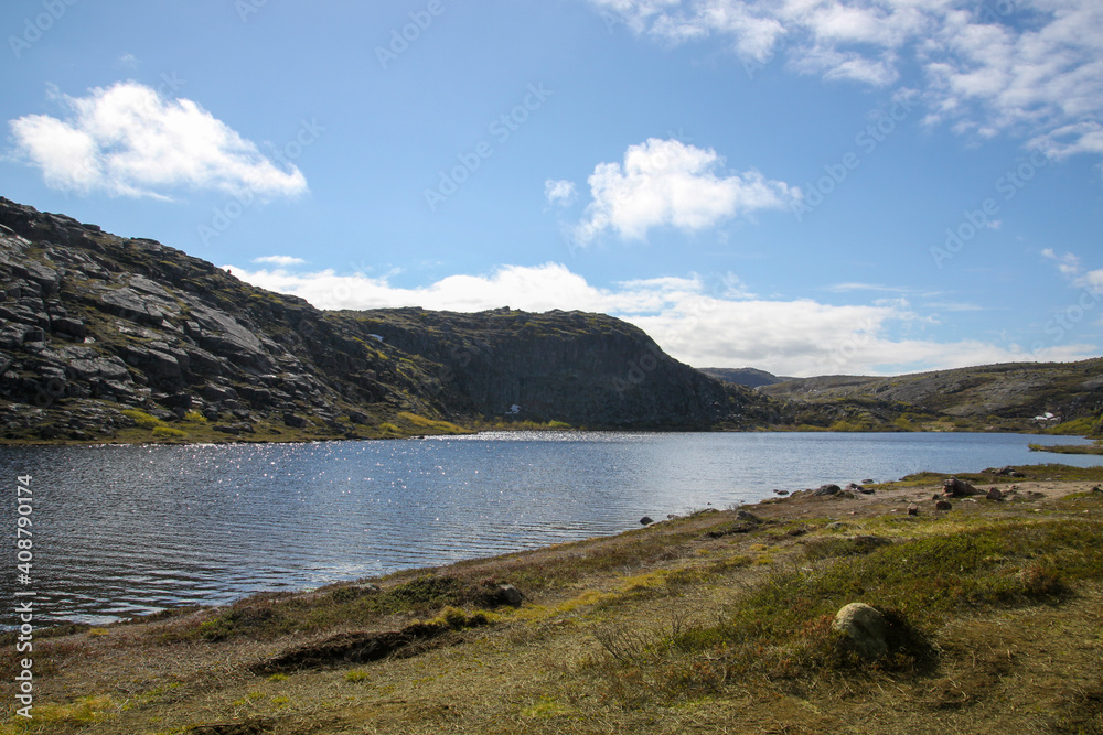 The lake in the hills on a bright sunny day. Beautiful summer landscape.
