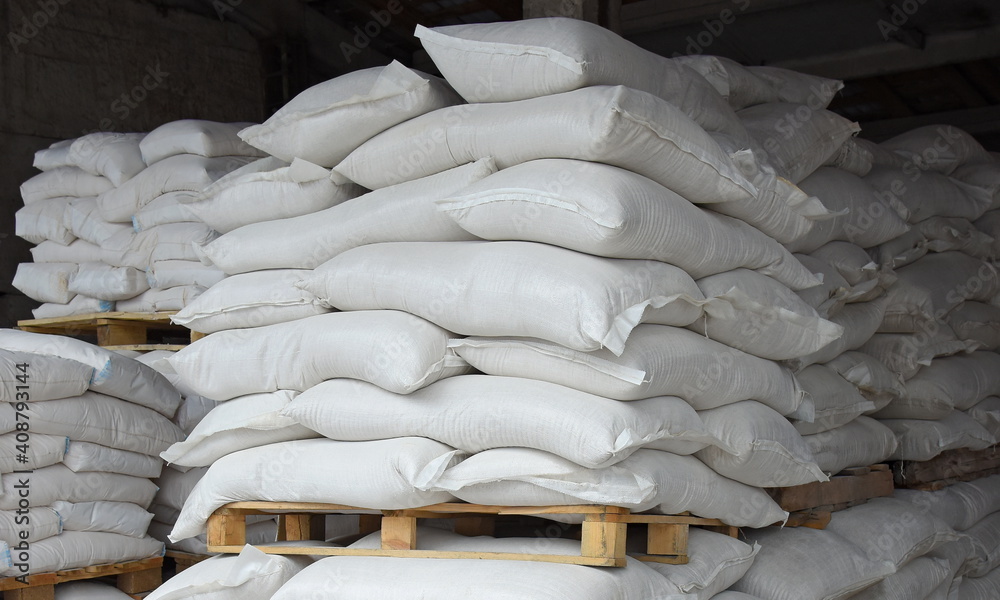 Bags of flour and grain in the warehouse are stacked on pallets, the factory is processing and sorting.