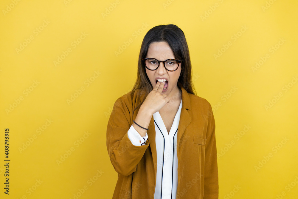 Young beautiful woman wearing a blazer over isolated yellow background disgusted with her hand inside her mouth Young beautiful woman wearing a blazer over isolated yellow background disgusted with her hand inside her mouth