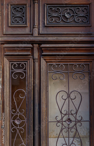 Old brown wooden door with rustic forged wrought iron ornaments