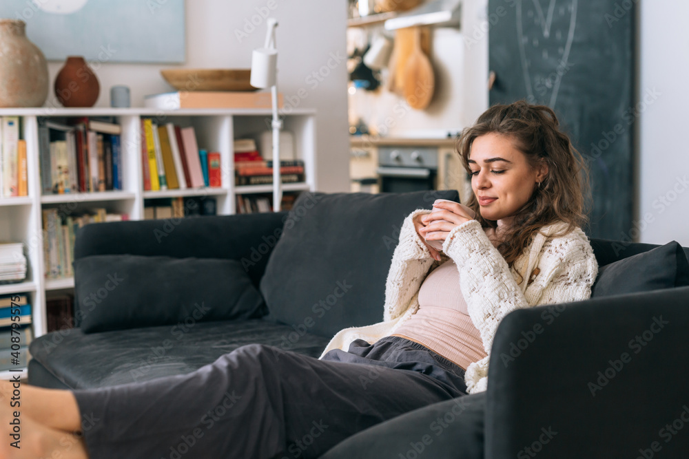 woman siting on sofa in her apartment and drinking morning coffee woman siting on sofa in her apartment and drinking morning coffee
