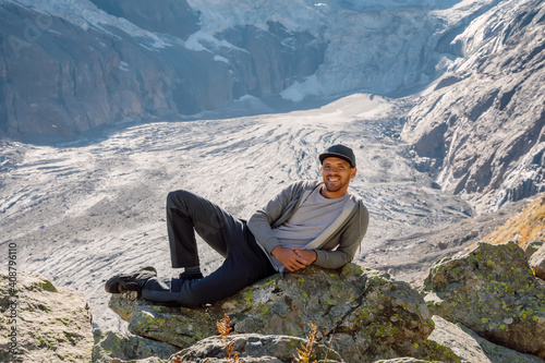 Smiling hiker man and the mountains at background. Glacier and happy tourist