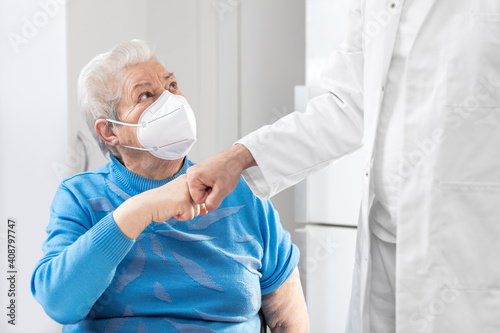 Female Senior adult with ffp2 mask is giving a doctor a fist bump photo