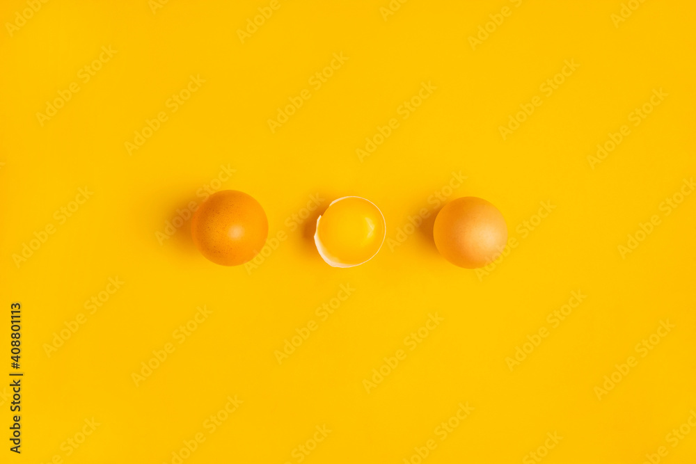 Three farm brown chicken eggs with one yolk on yellow table. Minimalistic product concept. Healthy food or Happy Easter concept. Top view, flat lay Three farm brown chicken eggs with one yolk on yellow table. Minimalistic product concept. Healthy food or Happy Easter concept. Top view, flat lay