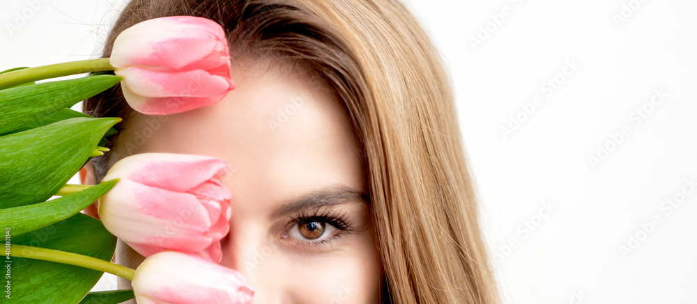 Half face portrait of a happy young caucasian woman with closed eyes and pink tulips cover her face against a white background Half face portrait of a happy young caucasian woman with closed eyes and pink tulips cover her face against a white background