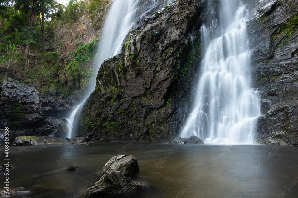 Fototapeta premium Waterfall in a tropical forest. Waterfalls in Kamphaeng Phet Province, Thailand. Landscape of the waterfall. Streams and rocks in the forest.