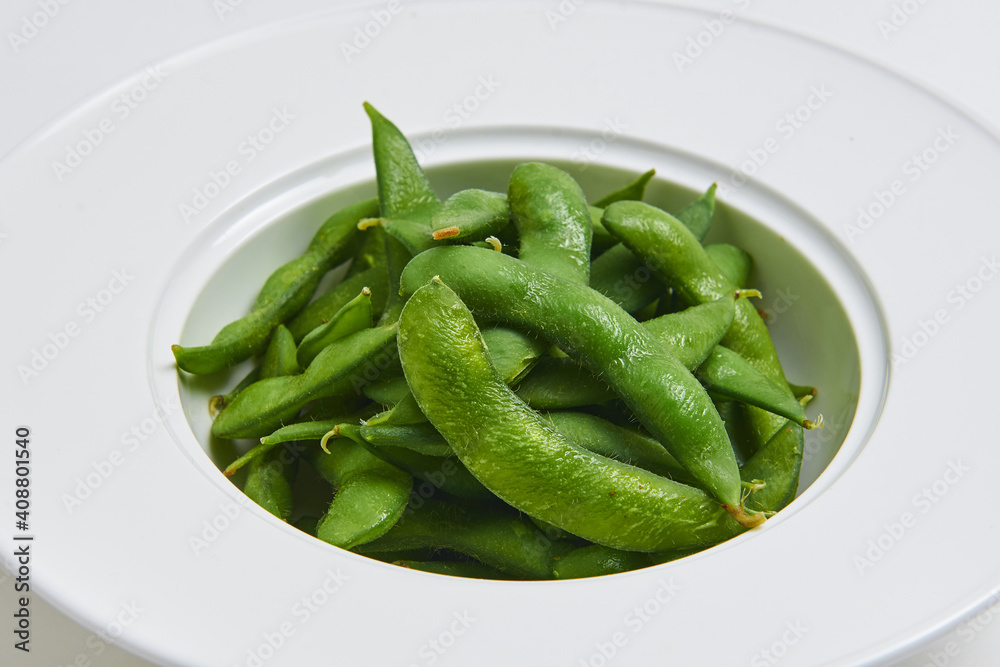 Hot Japanese Edamame Served on a white plate, appetizer menu Hot Japanese Edamame Served on a white plate, appetizer menu