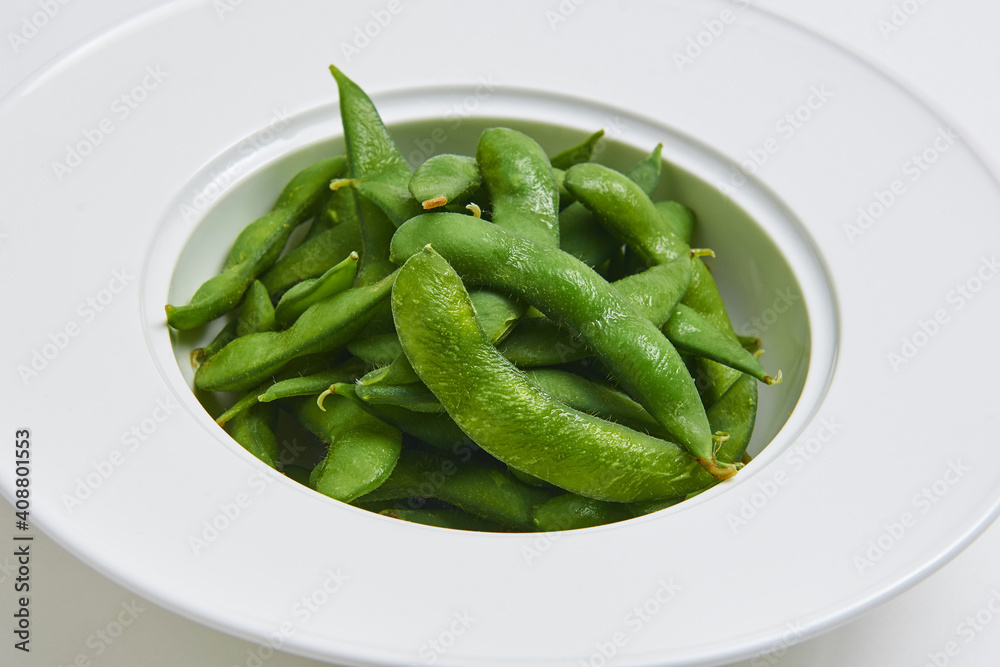 Hot Japanese Edamame Served on a white plate, appetizer menu Hot Japanese Edamame Served on a white plate, appetizer menu
