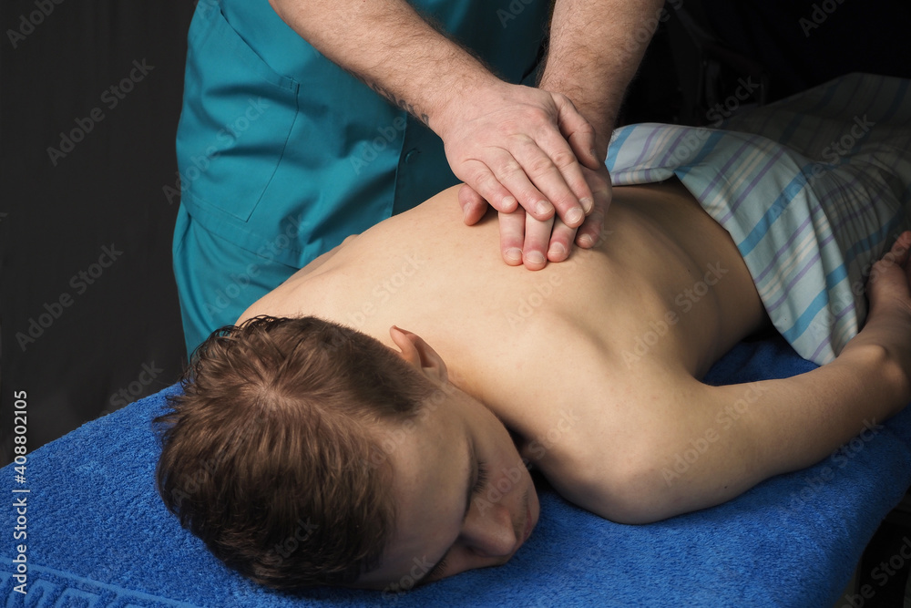 Back massage is therapeutic. A young man is lying on Back massage is therapeutic. A young man is lying on