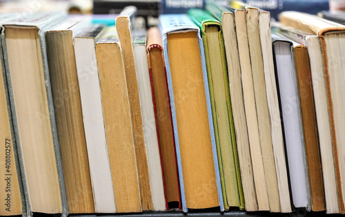 Row of many old used books displayed at local antiquarian bookshop, shallow depth of field photo, only few pages in focus