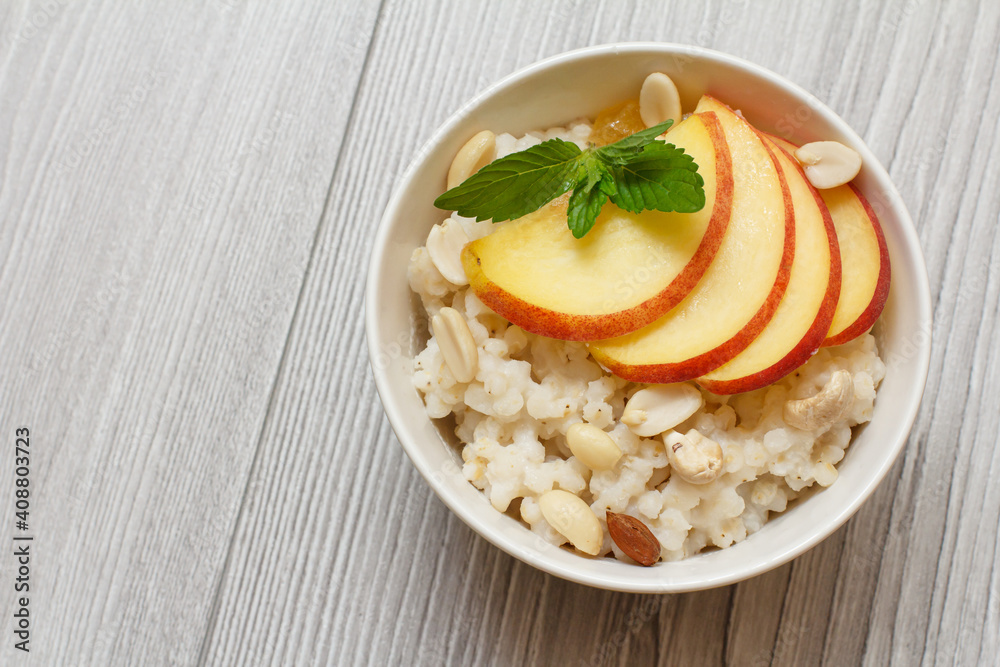 Sorghum salad with nuts and fresh peach on wooden background.