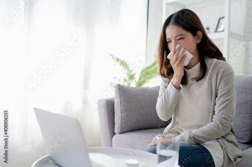 Young Asian women cough and sneeze while working at home. She feels sick.