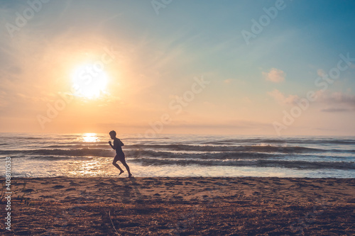 silhouette of jogging man on beach in the morning at sunrise. © TongTa