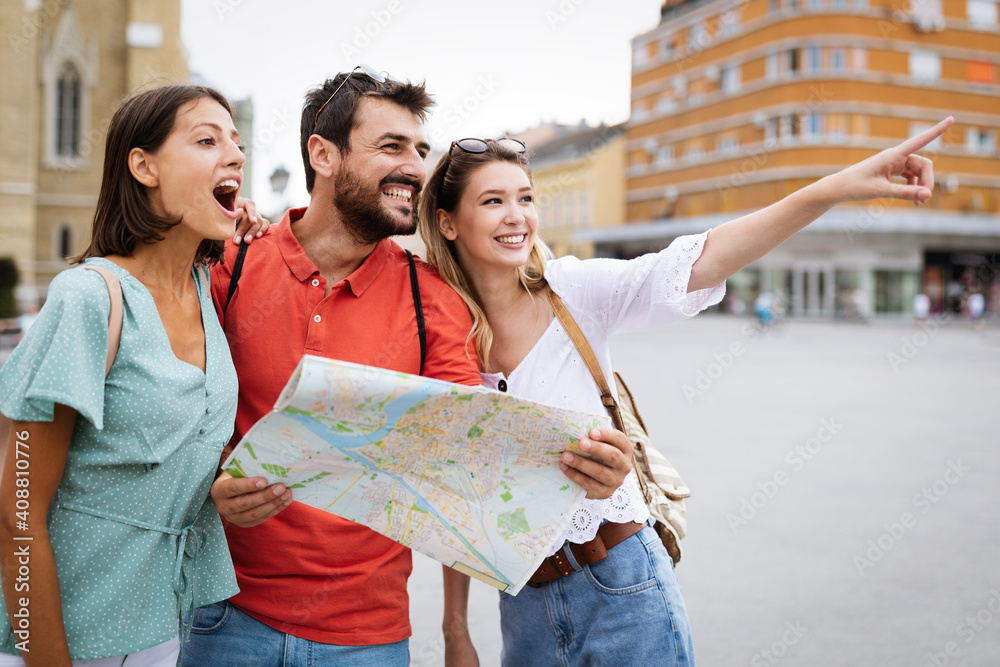 Happy traveling tourists sightseeing with map and having fun - obrazy, fototapety, plakaty 