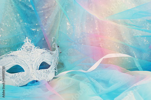 Photo of elegant and delicate Venetian mask over gold and blue chiffon background