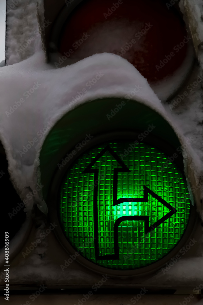 The evening traffic light is covered with snow.