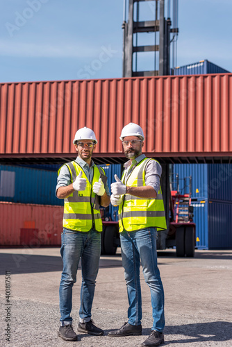 Logistics engineer and inspector working togetter and Thumbs up in shipping containerin commercial transport port