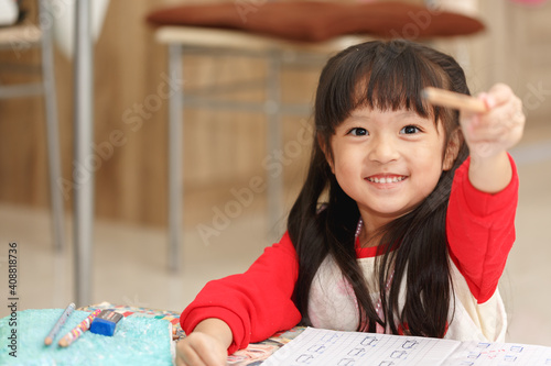 Asian little girl learning and writing in notebook with pencil