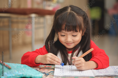 Asian little girl learning and writing in notebook with pencil