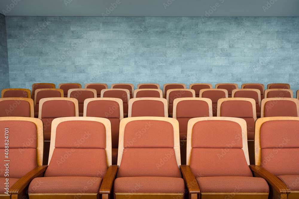 Fototapeta premium Row of brown theatre seats and marble wall in auditorium