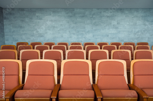 Row of brown theatre seats and marble wall in auditorium