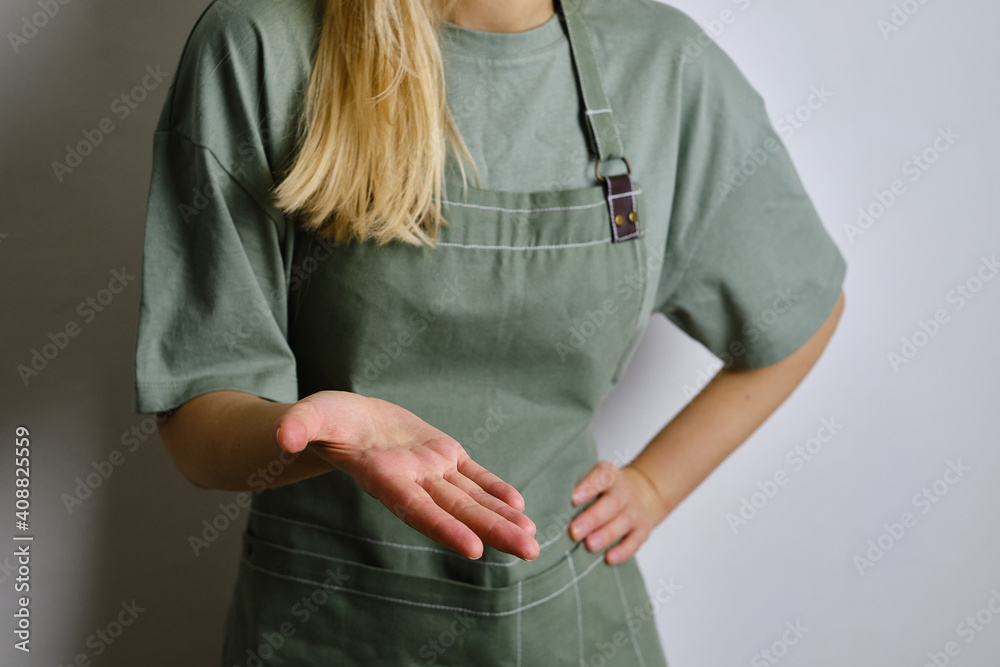 A woman in a kitchen apron. Chef work in the cuisine. Cook in uniform, protection apparel. Job in food service. Professional culinary. Green fabric apron, casual clothing. Handsome baker posing A woman in a kitchen apron. Chef work in the cuisine. Cook in uniform, protection apparel. Job in food service. Professional culinary. Green fabric apron, casual clothing. Handsome baker posing