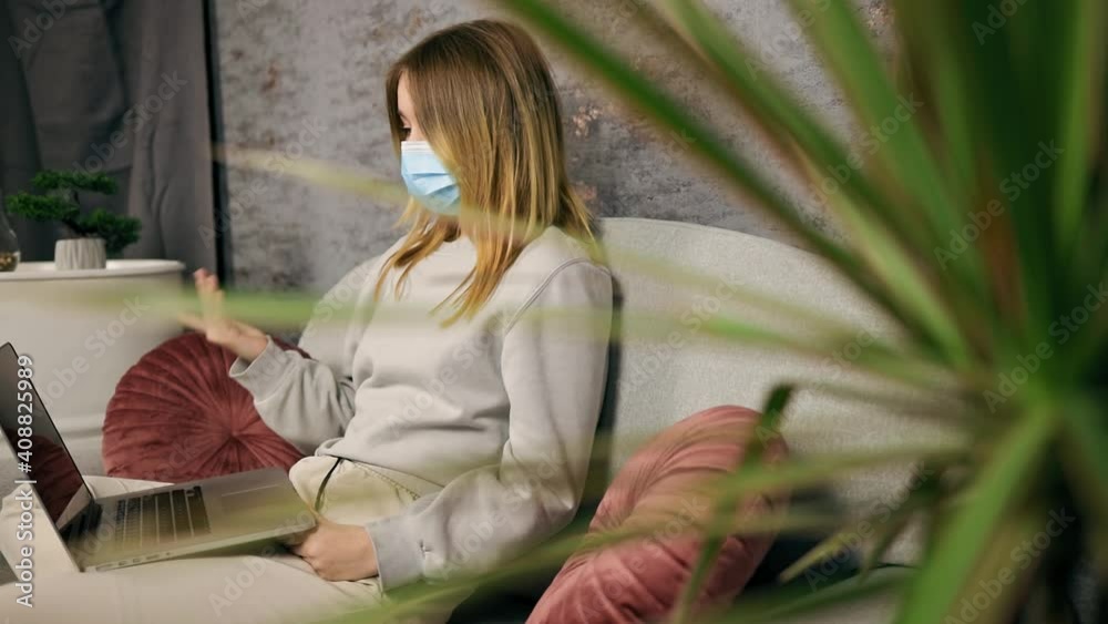 Blonde female blogger in medical mask live streaming her course using laptop