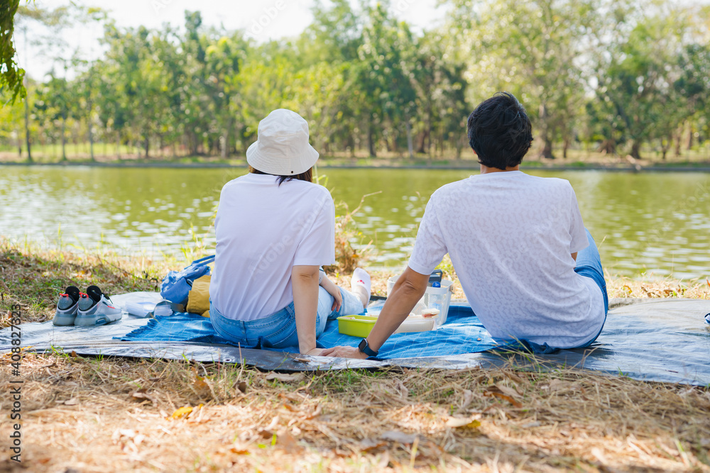 Fototapeta premium asian couple picnic with happiness feeling in park with lake in springtime