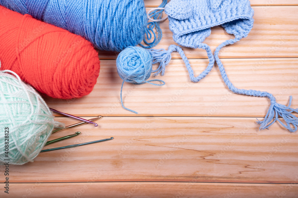 Skeins of wool and knitting needles  on wooden background with Space for text.