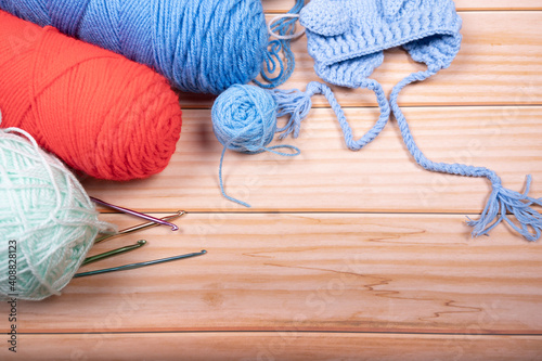 Skeins of wool and knitting needles on wooden background with Space for text.