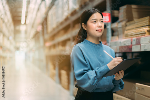 Portrait Young energetic smart Asian business working woman smile use digital tablet to check inventory data for product management in warehouse, Logistics business planning concept with copy space