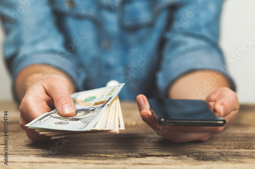 Fotografie Woman holds dollars and phone in her hands